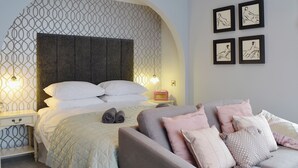 A bedroom with a bed, a nightstand, a chair, and wall art. - 2 bedroom accommodation in Aberystwyth (Aberystwyth)