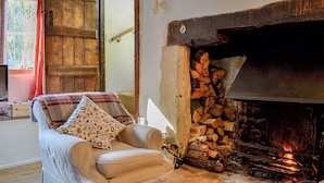 Una sala de estar acogedora con chimenea, un sofá con cojines estampados y una mesa de centro de madera.