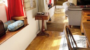 Una sala de estar acogedora con piso de madera, un sofá, una mesita y una chimenea.