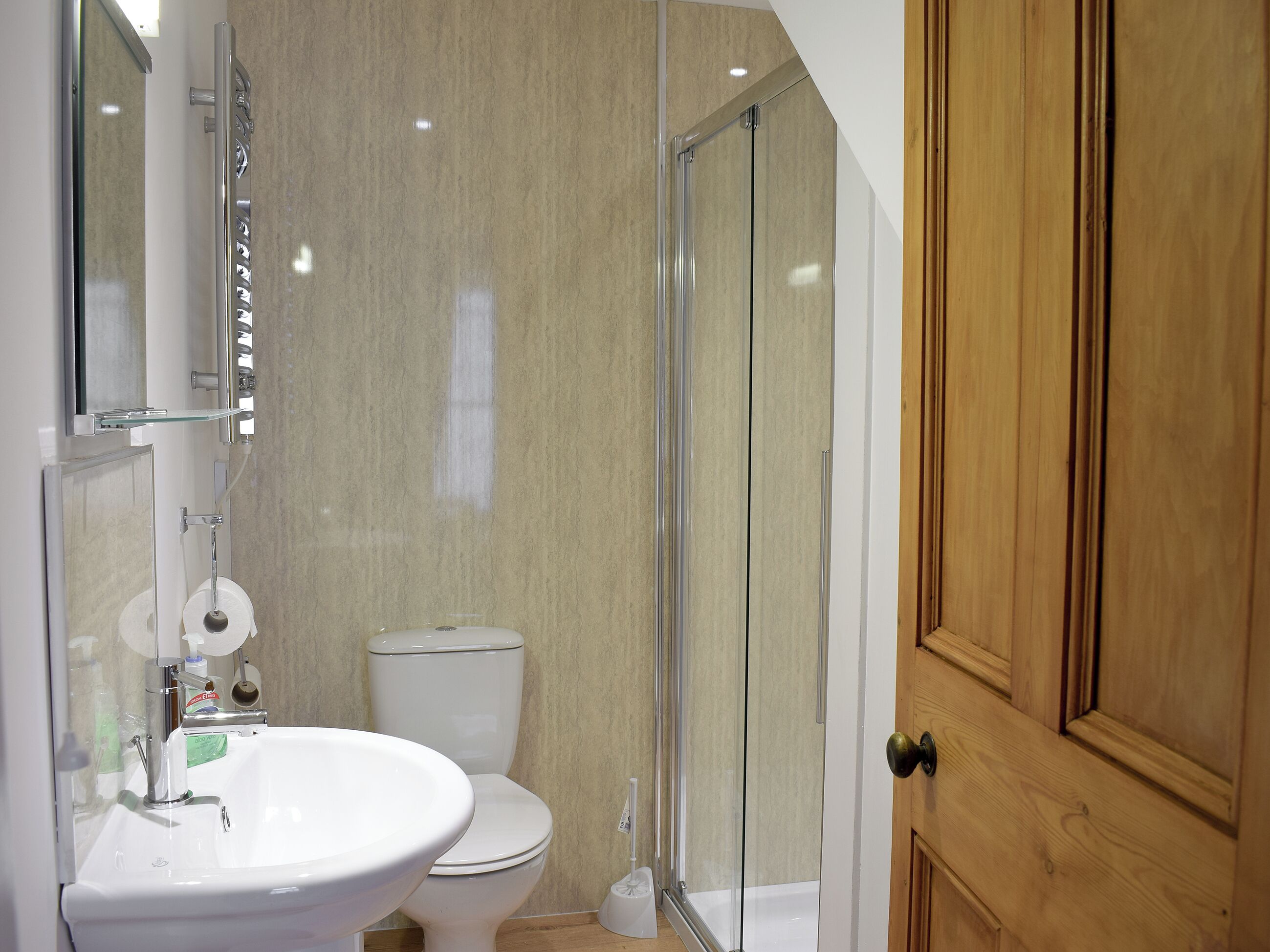 Ein Badezimmer mit weißem Waschbecken, Toilette und Duschkabine aus Glas.