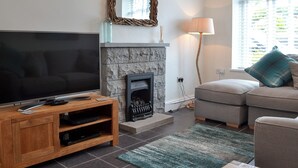 A living room with a TV, fireplace, sofa, and a window with blinds. - 3 bedroom accommodation in Criccieth, near Porthmadog (Criccieth, near Porthmadog)