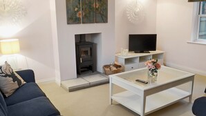 Ein Wohnzimmer mit einer Couch, einem Couchtisch, einem Kamin, einem Fernseher und dekorativer Wandgestaltung.