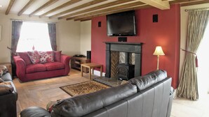Una sala de estar con chimenea, televisor montado en la pared y un sofá.