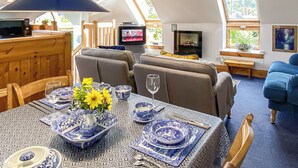 A cozy living room with a sofa, a television, and a dining area with a table set for two. - 2 bedroom accommodation in Linlithgow, near Edinburgh (Linlithgow, near Edinburgh)