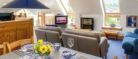 A cozy living room with a sofa, a television, and a dining area with a table set for two.