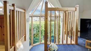 A room with a sloped ceiling, wooden beams, a large window, and a blue carpet. - 2 bedroom accommodation in Linlithgow, near Edinburgh (Linlithgow, near Edinburgh)