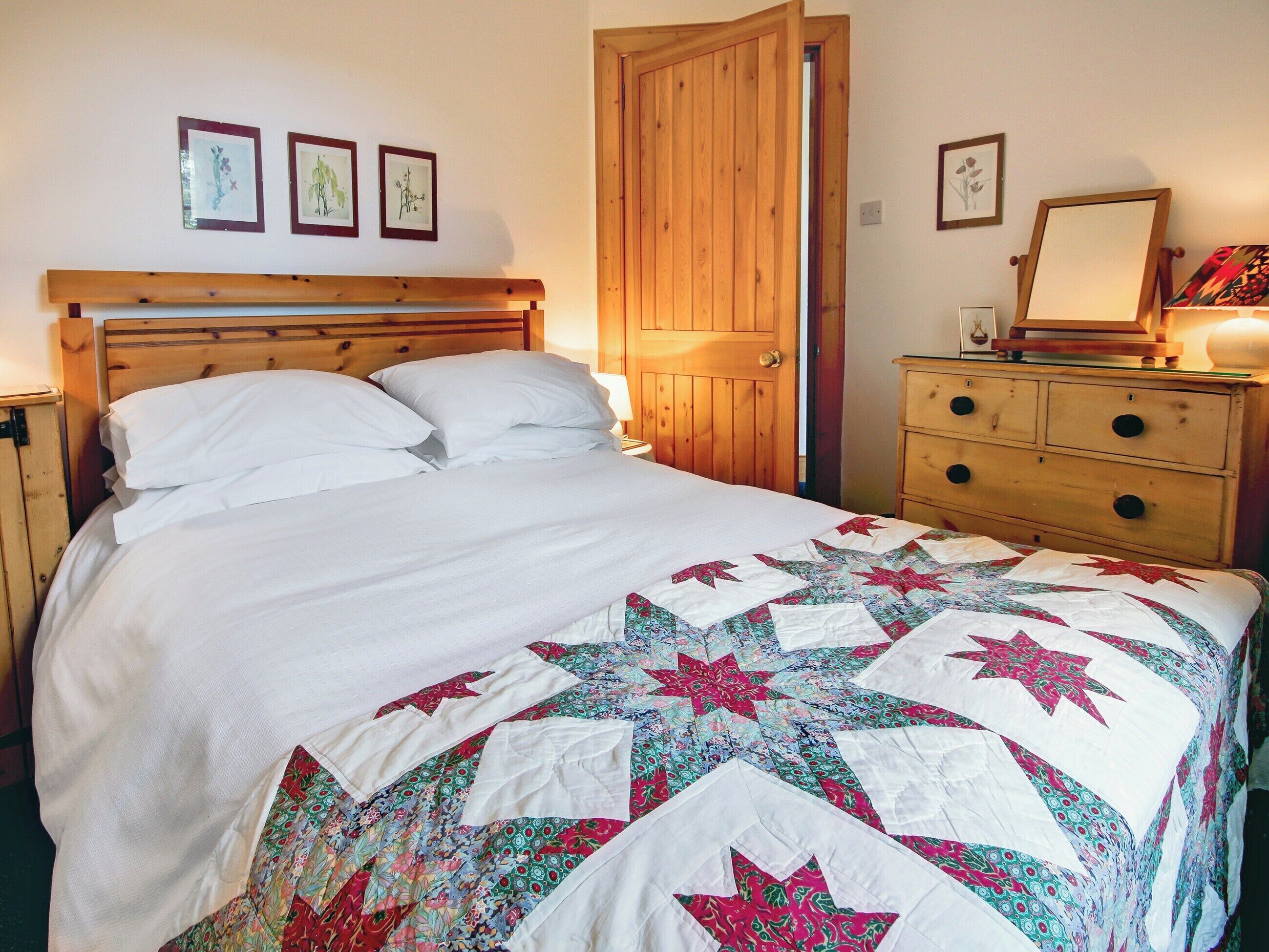 Ein Schlafzimmer mit einem hölzernen Bett, einem Schminktisch und einer Tür.