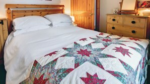 A bedroom with a wooden bed, a dresser, and a door. - 2 bedroom accommodation in Linlithgow, near Edinburgh (Linlithgow, near Edinburgh)