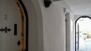 A hallway with white walls, a door with a number '2' and a black decorative element, and a black lantern on the wall.