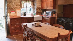 Une cuisine avec des meubles de rangement en bois, une cuisinière, un four à micro-ondes et une table à manger avec des chaises.