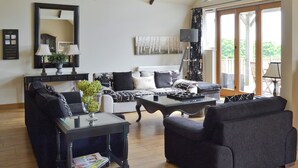 A living room with a sofa, coffee table, and a dining table. There is a large window with a view of the outdoors. - 4 bedroom accommodation in Killerby, near Scarborough (Killerby, near Scarborough)