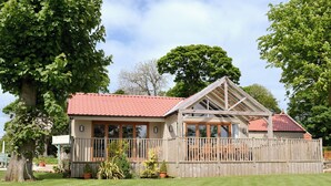 A wooden house with a red-tiled roof, large windows, and a fenced porch. - 4 bedroom accommodation in Killerby, near Scarborough (Killerby, near Scarborough)