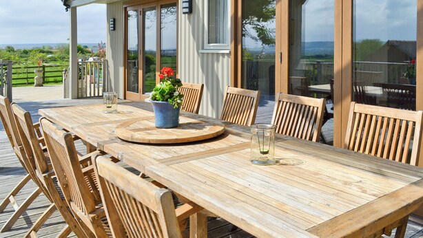 An outdoor wooden table with chairs, a potted plant, and a glass candle holder. - 4 bedroom accommodation in Killerby, near Scarborough (Killerby, near Scarborough)