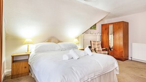 A bedroom with a large bed, two bedside tables with lamps, a wooden wardrobe, and a radiator. - 2 bedroom accommodation in Keith (Keith)
