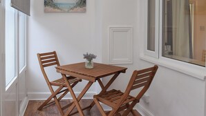 Un petit coin repas avec une table et des chaises en bois, un vase rempli de fleurs et un tableau accroché au mur.