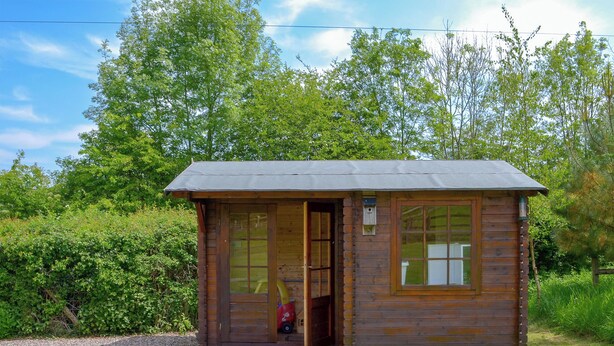 Une petite cabane en bois avec une porte, des fenêtres et une véranda.