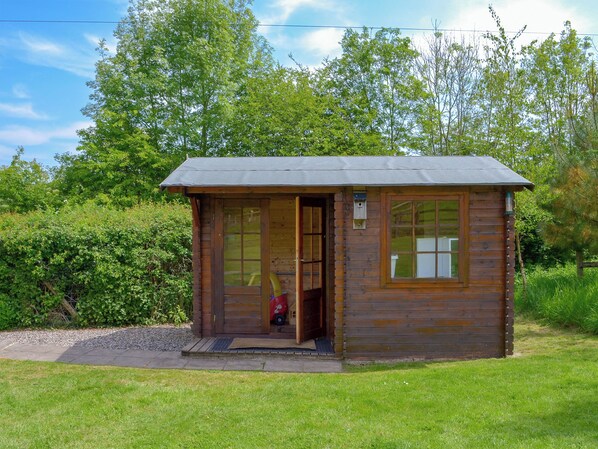 A small wooden cabin with a door, windows, and a porch. - Nestled in the Blackdown Hills, this barn is secluded and secure dog-friendly. (Dunkeswell Abbey, near Honiton)