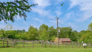 Un pâturage clôturé avec une structure en bois, des poteaux électriques et un ciel dégagé.