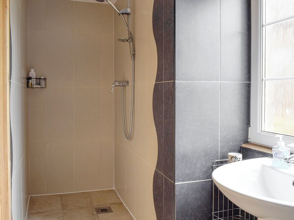 Un baño con ducha, lavamanos y ventana.