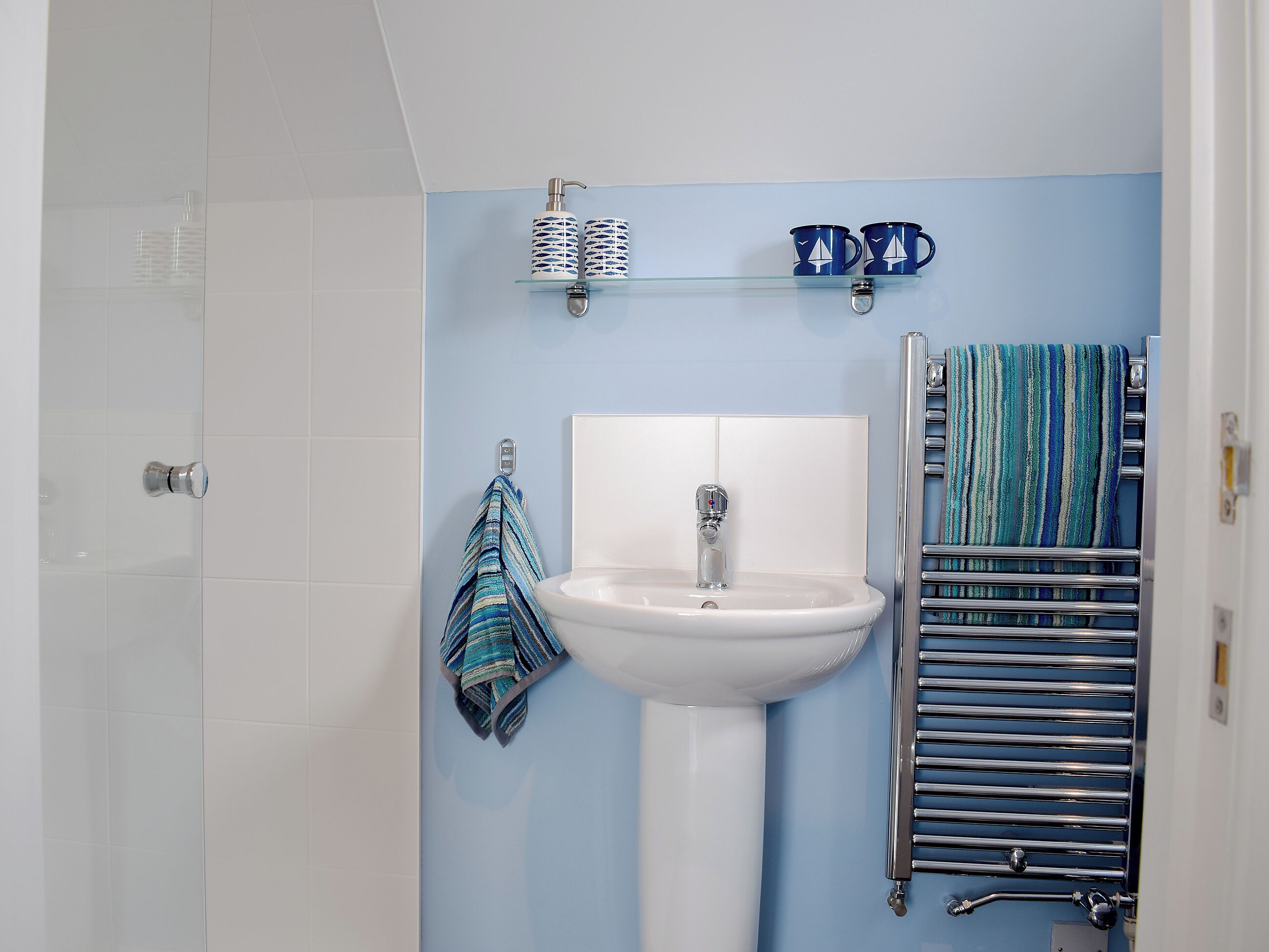 A bathroom with a white sink, a towel rack, and a towel hanging on it.