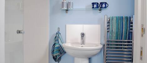 A bathroom with a white sink, a towel rack, and a towel hanging on it.