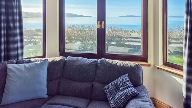 Una habitación con un sofá de color oscuro y vistas al mar a través de amplios ventanales.