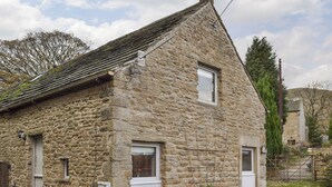 A stone building with a sloped roof, a small porch, and a door.