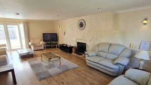 Ein Wohnzimmer mit einer Couch, einem Fernseher, einem Kamin und einem Couchtisch.