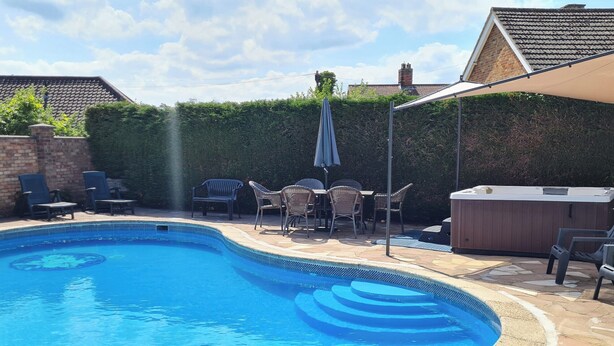 Ein Swimmingpool mit Whirlpool, Liegestühlen und einer Terrassenfläche.