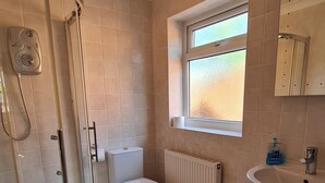 Ein Badezimmer mit Toilette, Dusche, Fenster und Waschbecken.