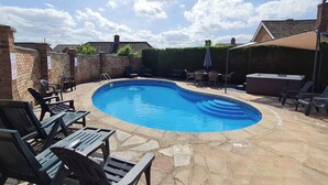 Ein Swimmingpool mit Liegestühlen und einem Whirlpool in einem Garten.