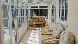 Ein sonnendurchflutetes Zimmer mit einer langen Bank, einem Sofa und einem Sessel.