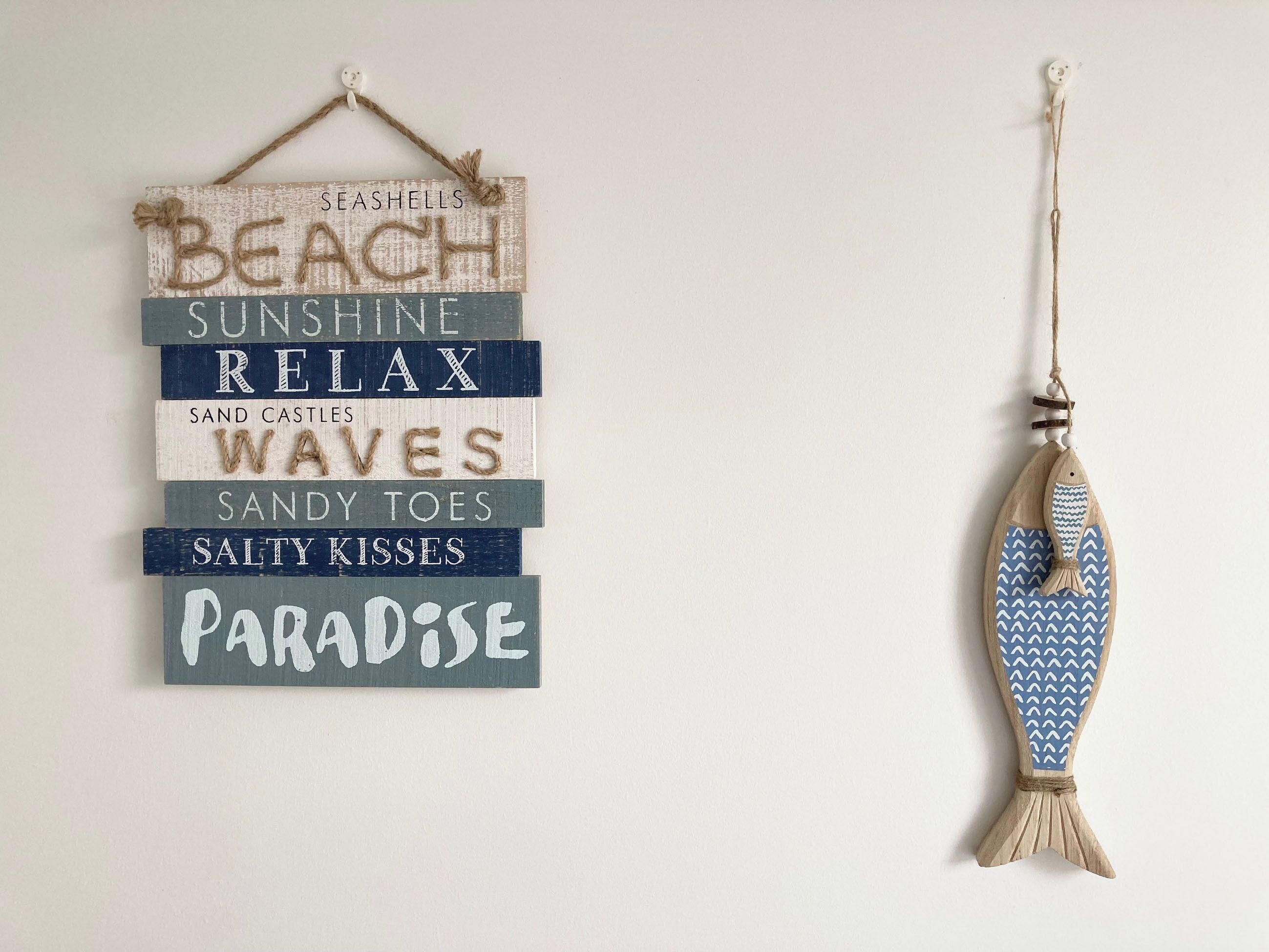 A wall decoration with nautical-themed words and a fish ornament.