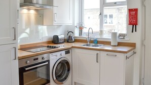 Eine kompakte Küche mit Einbauofen, Waschmaschine, Toaster und Spüle.