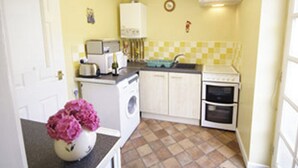 A compact kitchen with a washing machine, a toaster, a sink, and a small oven. - 1 bedroom accommodation in Aylsham (Aylsham)
