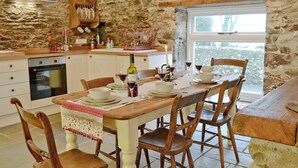 Una cucina rustica con pareti in pietra, mobili in legno e un tavolo da pranzo apparecchiato per quattro persone.