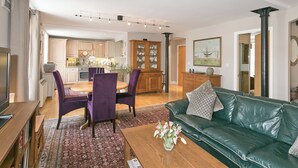 A spacious living room with a green leather sofa, a dining area with purple chairs, and a kitchen in the background. - Jorvik- Woodsmill Quay (Skeldergate, York)