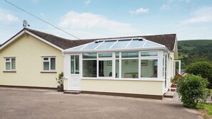 A house with a conservatory, a driveway, and a view of the countryside. - 3 bedroom accommodation in Llangenny, near Crickhowell (Llangenny, near Crickhowell)