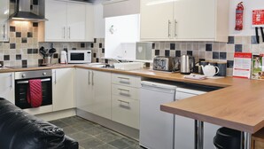 Eine moderne Küche mit weißen Schränken, einer Mikrowelle, einem Toaster, einem Wasserkocher und einem Feuerlöscher.