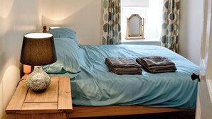 Ein Schlafzimmer mit einem Bett, einem Nachttisch mit Lampe und Vorhängen.
