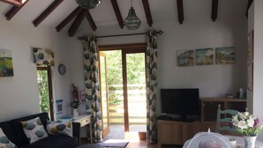 A cozy living room with a sofa, a coffee table, a TV, and a dining area with a table set for two. - 1 bedroom accommodation in Instow, near Barnstaple (Instow, near Barnstaple)