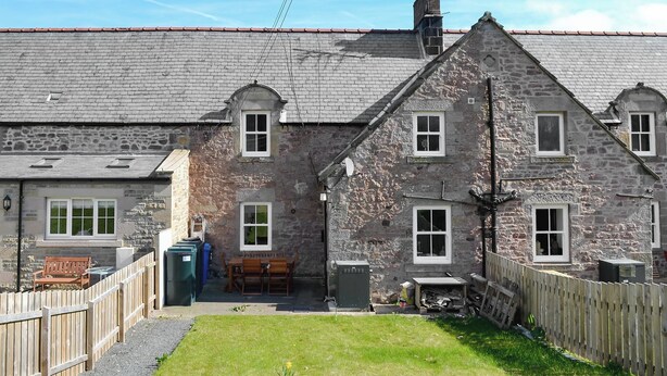 A stone building with multiple windows, a chimney, and a small garden area with a wooden fence. - 2 bedroom accommodation in Belford, near Alnwick (Belford, near Alnwick)