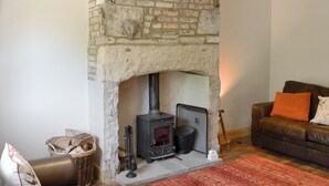 A cozy living room with a stone fireplace, a sofa, and a red rug. - 2 bedroom accommodation in Belford, near Alnwick (Belford, near Alnwick)