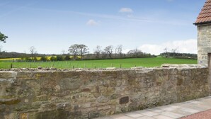 A stone wall with a paved walkway leading to a building with a red roof. - 2 bedroom accommodation in Longdyke, near Morpeth (Longdyke, near Morpeth)