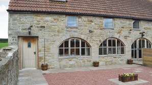 A stone building with a tiled roof, arched windows, and a door. - 2 bedroom accommodation in Longdyke, near Morpeth (Longdyke, near Morpeth)