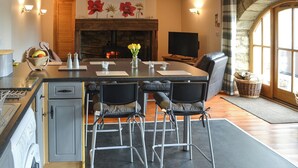 A modern kitchen with a central island, bar stools, a fireplace, and a television. - 2 bedroom accommodation in Longdyke, near Morpeth (Longdyke, near Morpeth)