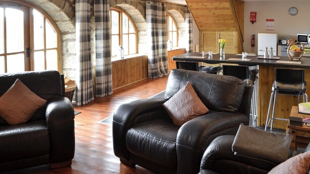 A spacious living area with leather sofas, a wooden dining table, and large arched windows. - 2 bedroom accommodation in Longdyke, near Morpeth (Longdyke, near Morpeth)