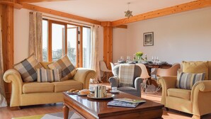 A cozy living room with a sofa, armchairs, a coffee table, and a dining table set for a meal. - 4 bedroom accommodation in Balmullo, near St Andrews (Balmullo, near St Andrews)