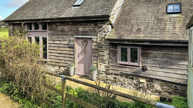 Un edificio rústico de piedra con una puerta de madera y una ventana pequeña.