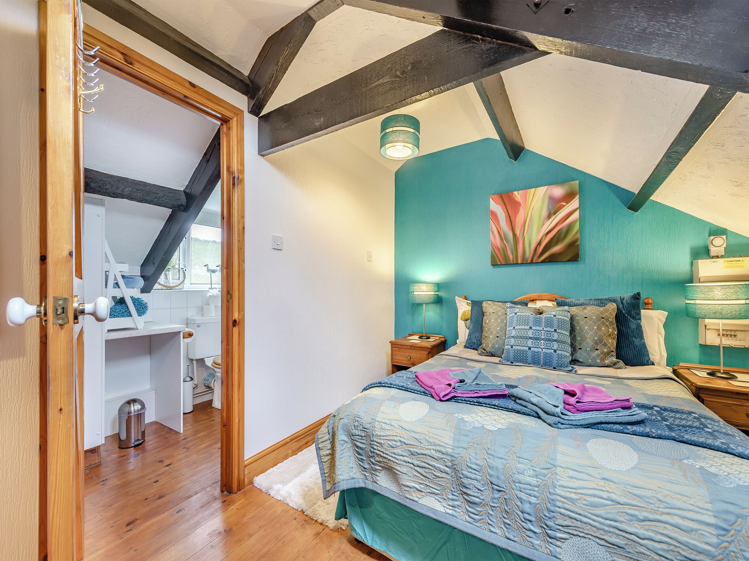 A bedroom with a bed, bedside tables, a wall-mounted lamp, and a ceiling light fixture.